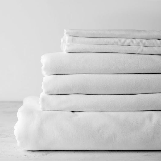 T-300 Flat Sheets by Thomaston Mills, perfect for hotels, offering comfort and practicality in white, stacked neatly.