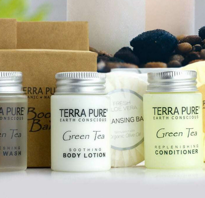 A set of Terra Pure Earth Conscious body care products including body wash, body lotion, conditioner, shampoo, cleansing bar, and a brown paper box, arranged on a white surface with soap and dried botanicals in the background.